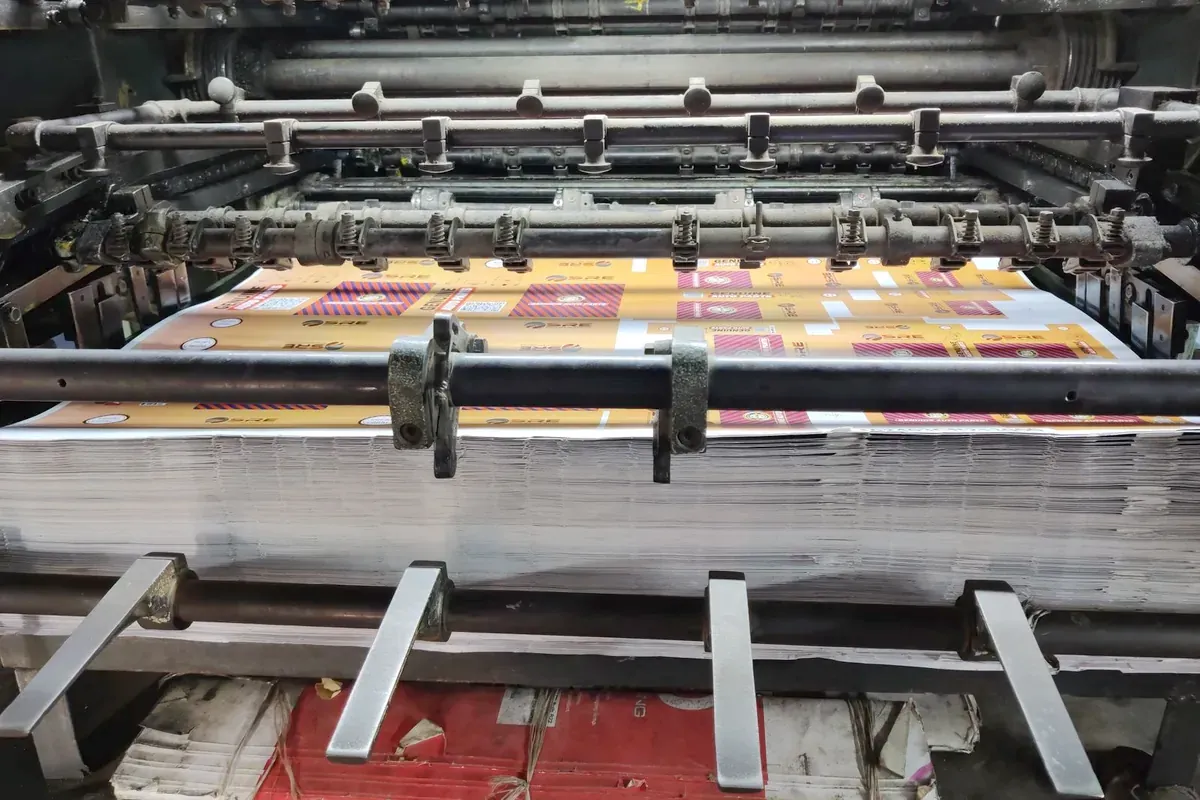 Bogenoffset-Druckmaschine mit bedrucktem Bogen in einer Druckerei