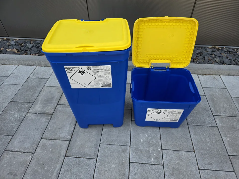 Zwei blaue Sammelbehälter mit gelbem Deckel und Gefahrgutkennzeichnung